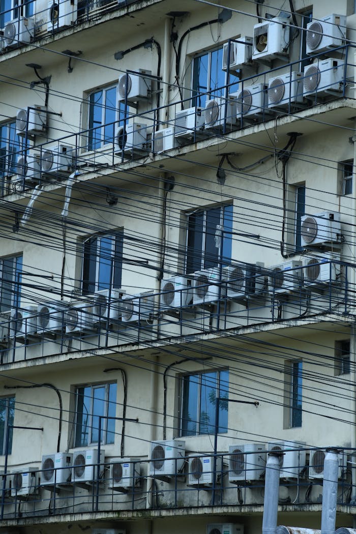 Facade of an urban residential building with multiple air conditioners and balconies.